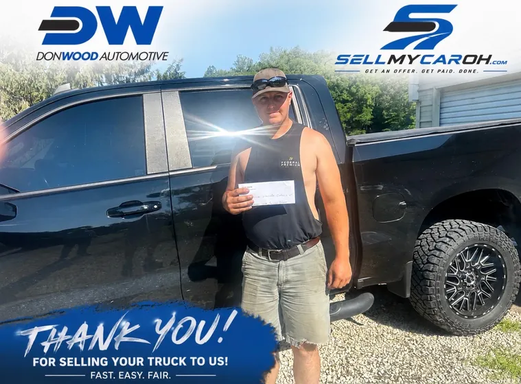 Seller holding his check after selling a black Chevy Silverado to SellMyCarOH