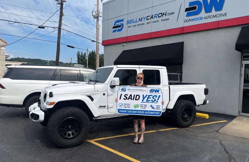 Customer holding an I Said Yes sign after selling her white Jeep Gladiator